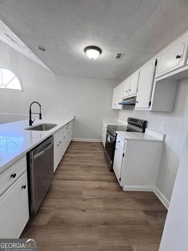 kitchen with dark wood-style floors, appliances with stainless steel finishes, under cabinet range hood, white cabinetry, and a sink