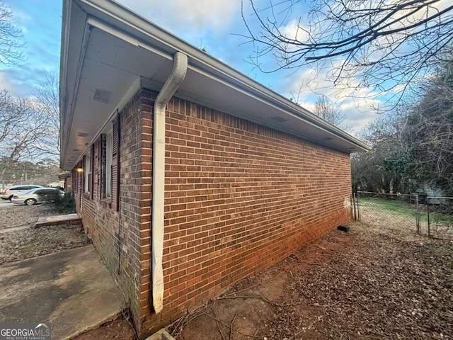 view of home's exterior with brick siding and fence