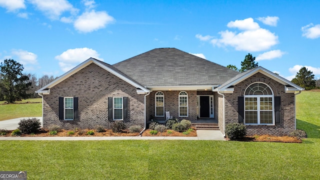 ranch-style home with roof with shingles, a front lawn, and brick siding