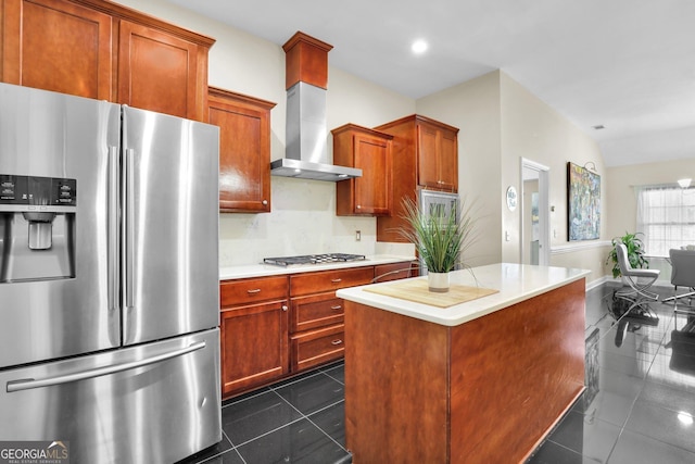 kitchen featuring a center island, stainless steel appliances, light countertops, wall chimney range hood, and dark tile patterned flooring