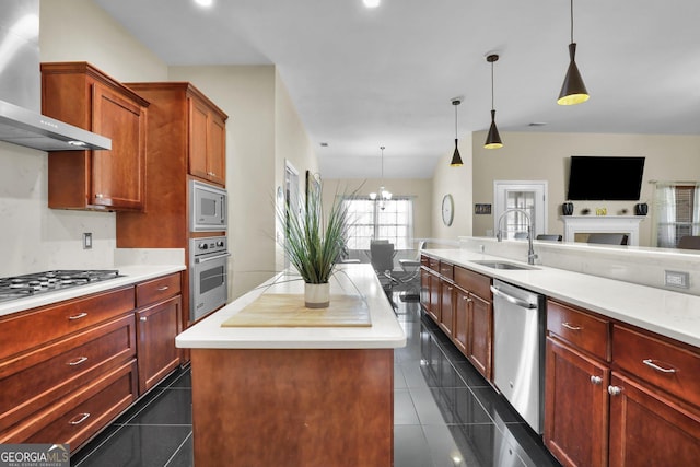 kitchen featuring open floor plan, stainless steel appliances, wall chimney range hood, dark tile patterned floors, and a sink