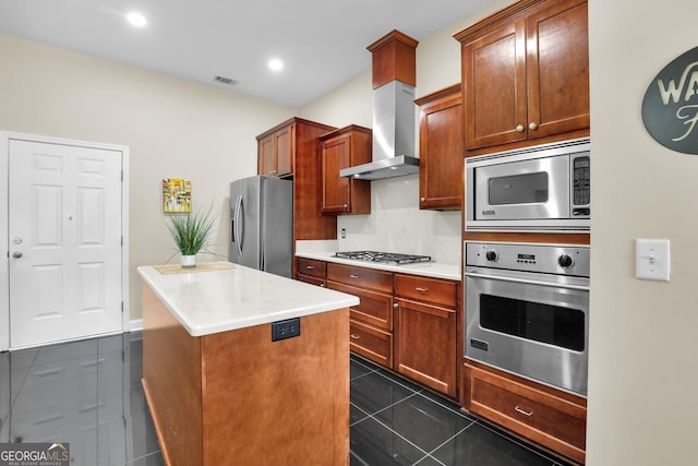 kitchen with a center island, visible vents, appliances with stainless steel finishes, dark tile patterned floors, and wall chimney exhaust hood