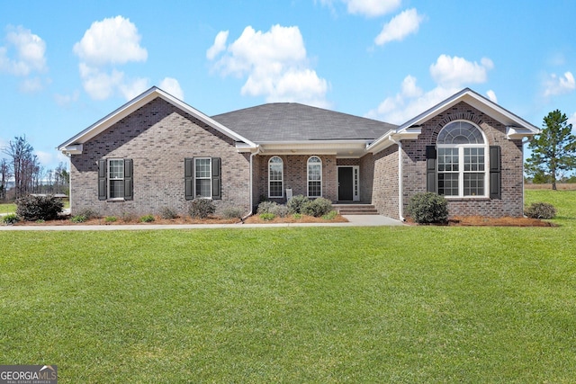 single story home featuring a front lawn, a shingled roof, and brick siding