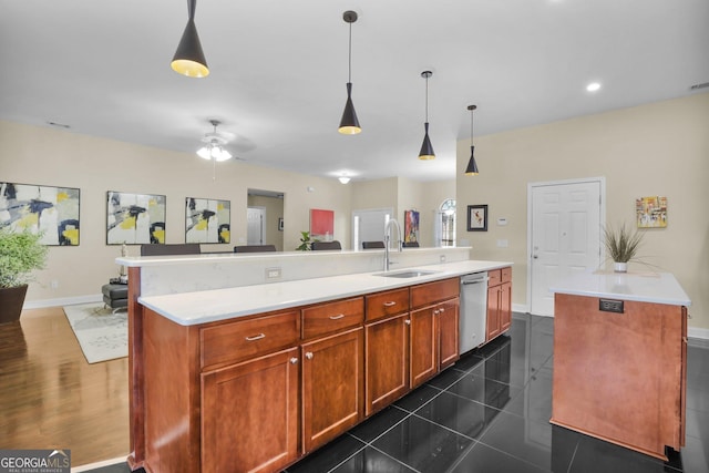 kitchen featuring dishwasher, light countertops, a sink, and a center island with sink