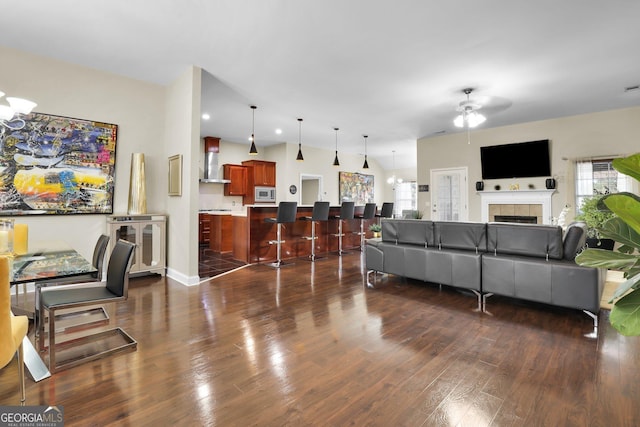 living area featuring a healthy amount of sunlight, dark wood-style floors, a fireplace, and a ceiling fan