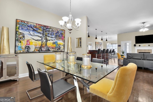 dining area with ceiling fan with notable chandelier, a tile fireplace, baseboards, and wood finished floors