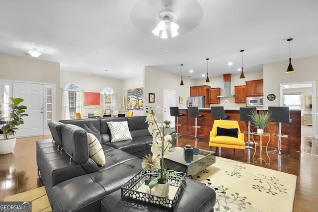 living room featuring ceiling fan with notable chandelier, dark wood finished floors, and recessed lighting