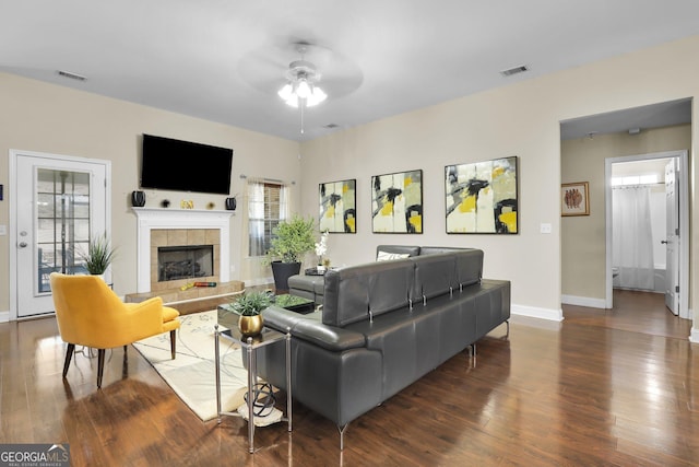 living area with wood finished floors, a tile fireplace, and visible vents