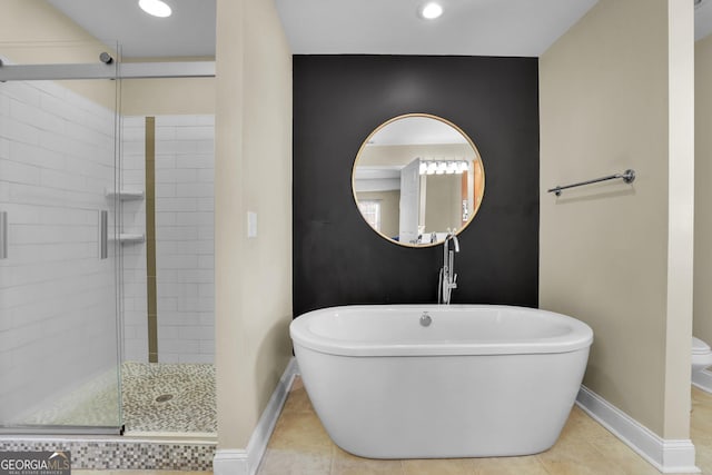 full bathroom with tile patterned floors, a soaking tub, a shower stall, and baseboards