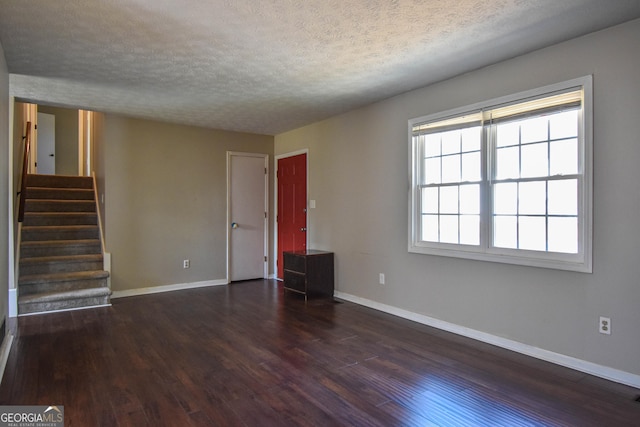 spare room featuring a textured ceiling, stairs, baseboards, and dark wood-style flooring