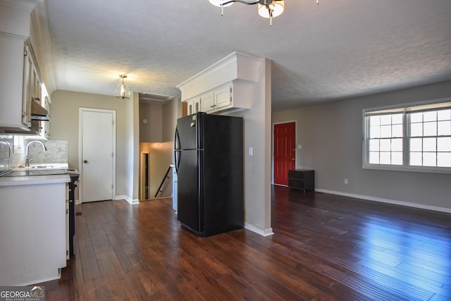 kitchen with tasteful backsplash, white cabinets, dark wood-style flooring, freestanding refrigerator, and light countertops