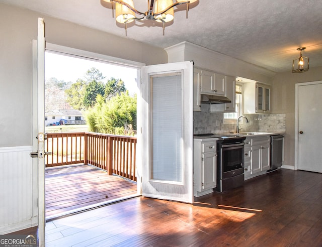 kitchen featuring under cabinet range hood, stainless steel appliances, a sink, dark wood finished floors, and an inviting chandelier