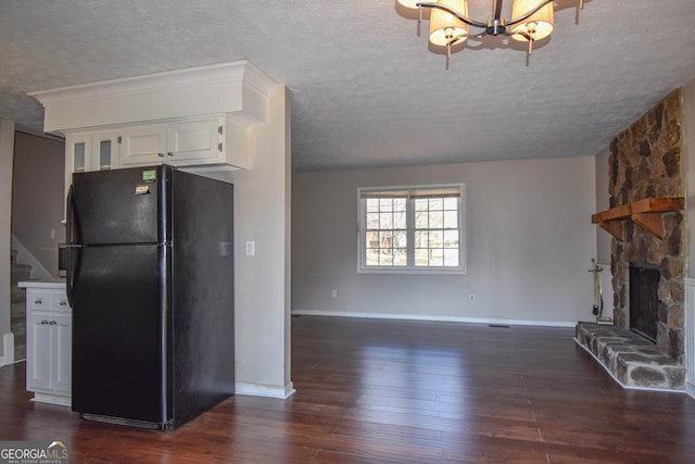 kitchen featuring dark wood-type flooring, a fireplace, freestanding refrigerator, and white cabinets