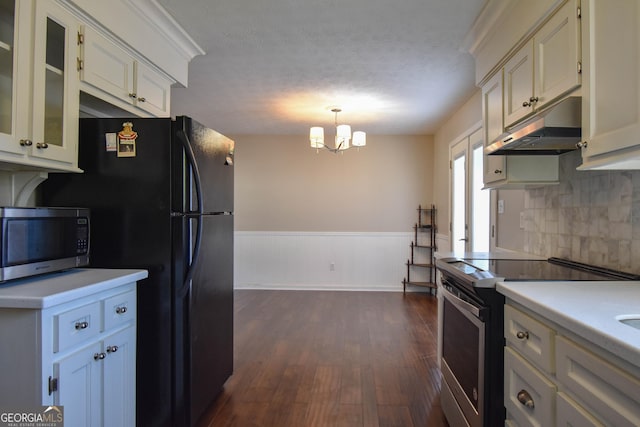 kitchen with a wainscoted wall, light countertops, appliances with stainless steel finishes, dark wood-type flooring, and under cabinet range hood