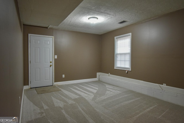 carpeted empty room featuring visible vents, a textured ceiling, and baseboards