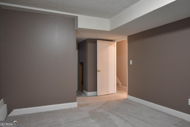 below grade area with a textured ceiling, carpet floors, and baseboards