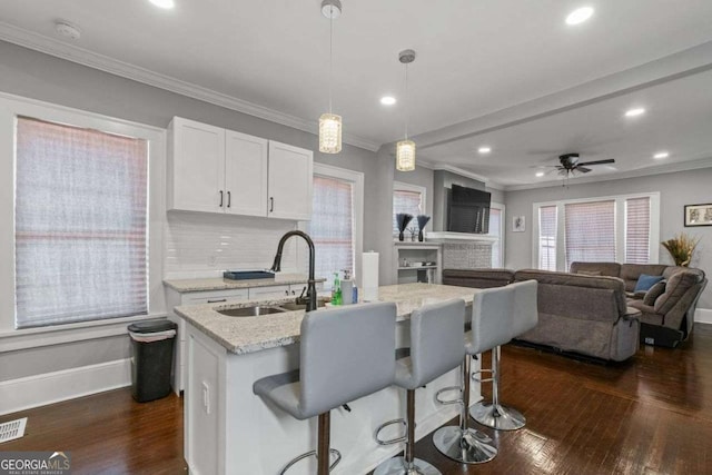 kitchen featuring light stone counters, dark wood-style flooring, a sink, and white cabinetry