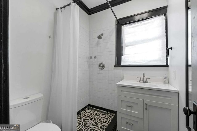 full bathroom with tiled shower, vanity, toilet, and crown molding