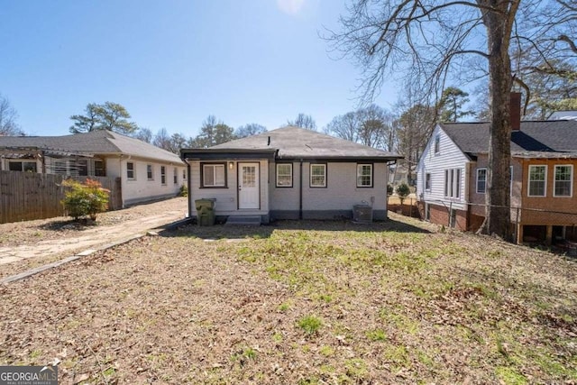 bungalow-style home with cooling unit, fence, and a front yard