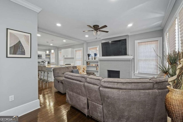 living room with ornamental molding, a brick fireplace, baseboards, and wood finished floors