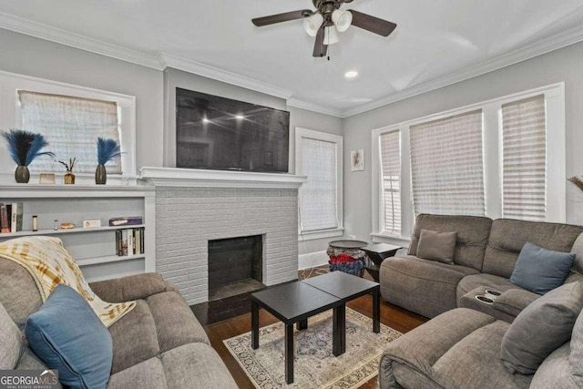 living area with a brick fireplace, ceiling fan, ornamental molding, and wood finished floors