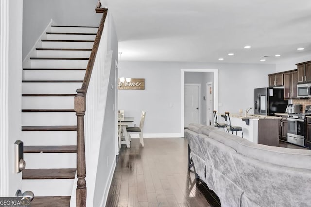 living area featuring stairs, baseboards, dark wood finished floors, and recessed lighting