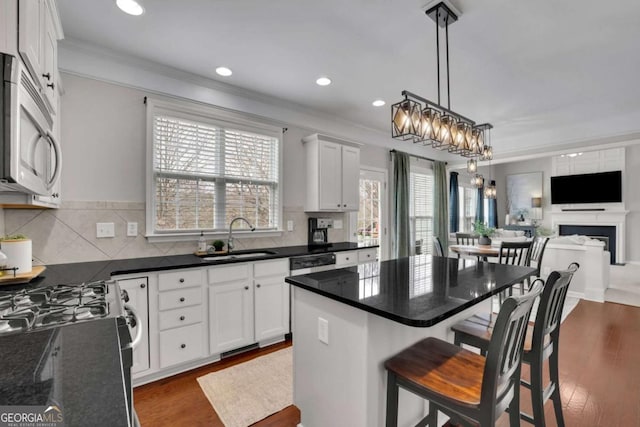 kitchen with dark wood-style floors, range with gas cooktop, tasteful backsplash, stainless steel microwave, and a sink