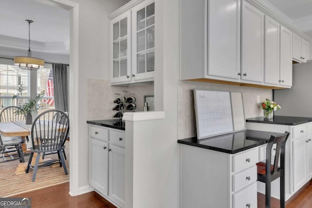 kitchen featuring dark countertops, decorative backsplash, white cabinets, and dark wood-style flooring