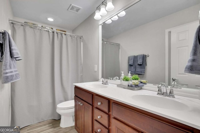 bathroom featuring double vanity, wood finished floors, a sink, and visible vents