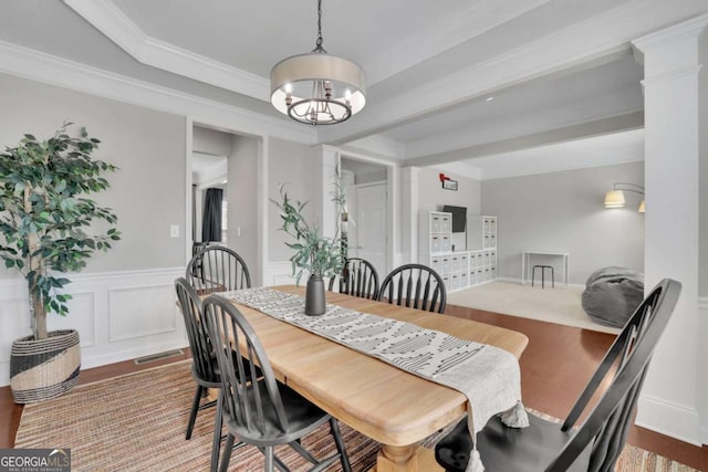 dining space featuring visible vents, a wainscoted wall, ornamental molding, wood finished floors, and an inviting chandelier