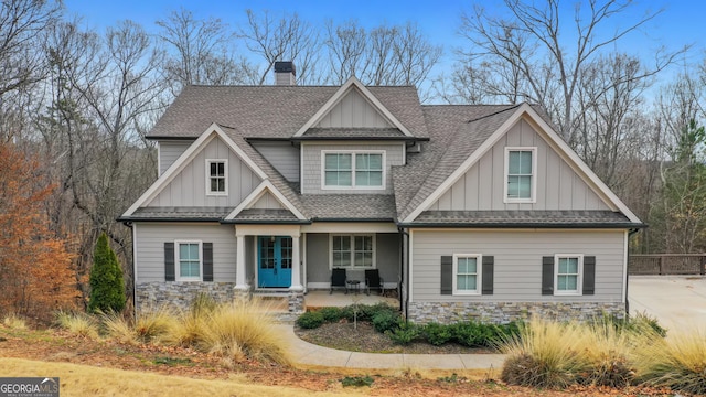 craftsman inspired home with board and batten siding, stone siding, roof with shingles, and a chimney