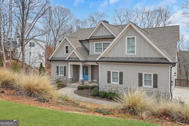 craftsman house featuring a shingled roof, a chimney, a front lawn, and board and batten siding