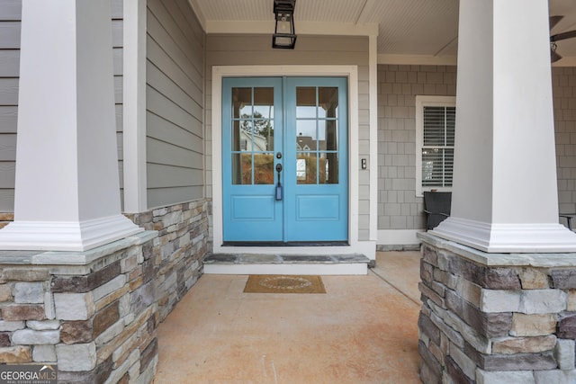 property entrance featuring stone siding, french doors, and covered porch