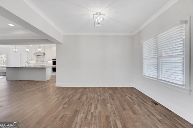 unfurnished living room with crown molding, visible vents, baseboards, and a notable chandelier