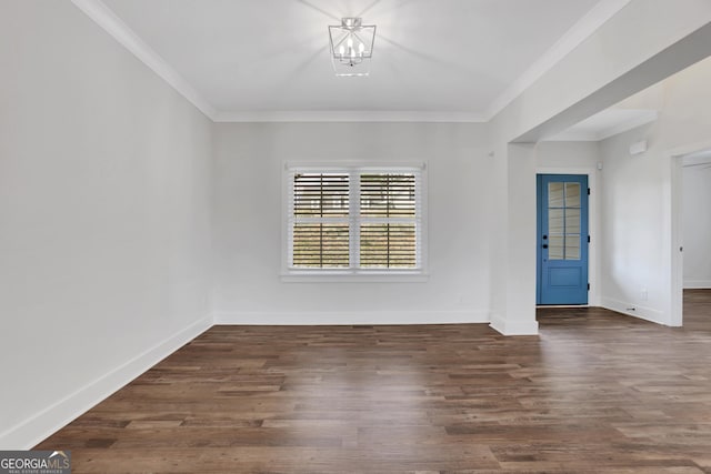 spare room with ornamental molding, a chandelier, baseboards, and wood finished floors