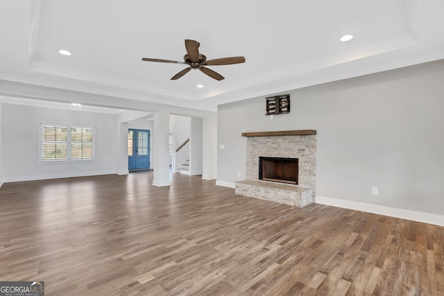 unfurnished living room with wood finished floors, a raised ceiling, and baseboards