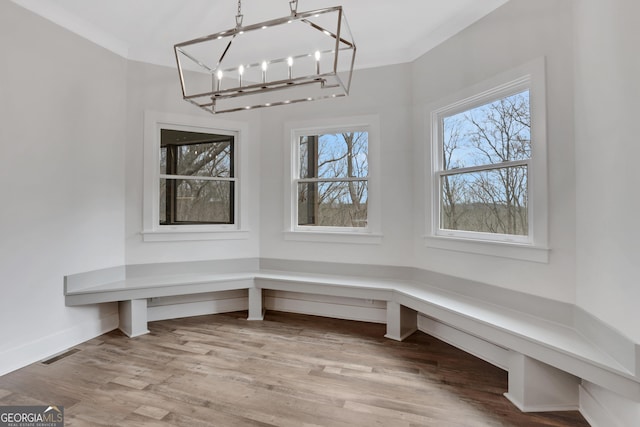 interior space featuring a chandelier, wood finished floors, visible vents, baseboards, and ornamental molding