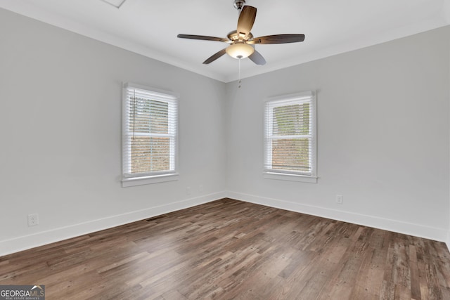 empty room with visible vents, crown molding, baseboards, and wood finished floors