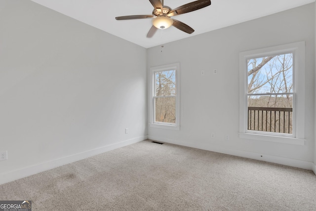 empty room featuring carpet floors, plenty of natural light, visible vents, and baseboards