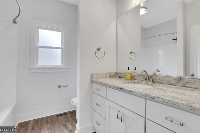 full bathroom with toilet, wood finished floors, vanity, visible vents, and baseboards