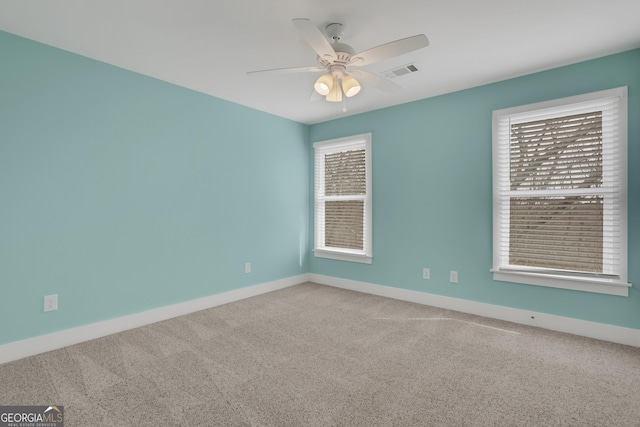 spare room with carpet floors, ceiling fan, visible vents, and baseboards