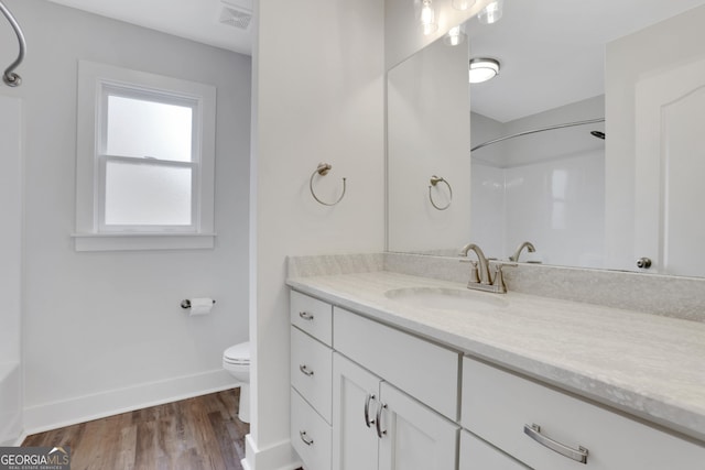 bathroom with visible vents, toilet, vanity, wood finished floors, and baseboards