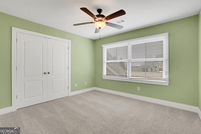 unfurnished bedroom with carpet, a closet, visible vents, a ceiling fan, and baseboards