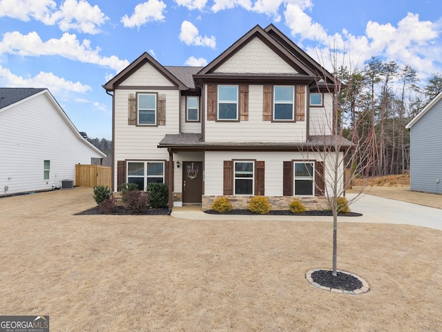 craftsman-style home featuring stone siding, fence, and central air condition unit