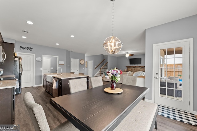 dining space featuring dark wood-style flooring, recessed lighting, an inviting chandelier, baseboards, and stairs