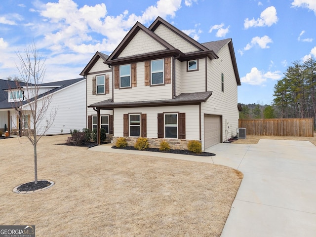 craftsman inspired home featuring an attached garage, central air condition unit, fence, concrete driveway, and stone siding