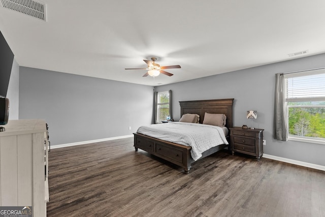 bedroom with a ceiling fan, wood finished floors, visible vents, and baseboards