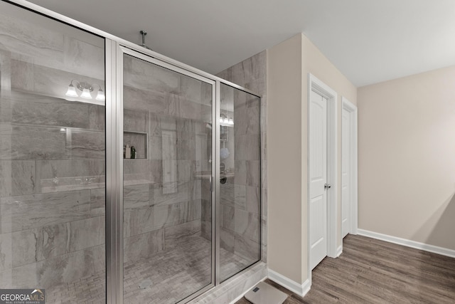 bathroom with a shower stall, baseboards, and wood finished floors