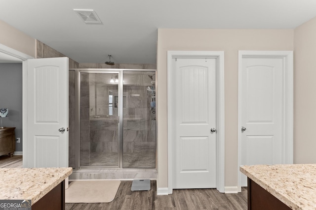 full bathroom featuring visible vents, a stall shower, vanity, wood finished floors, and baseboards