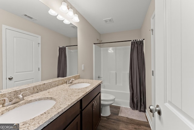 bathroom featuring double vanity, visible vents, a sink, and wood finished floors